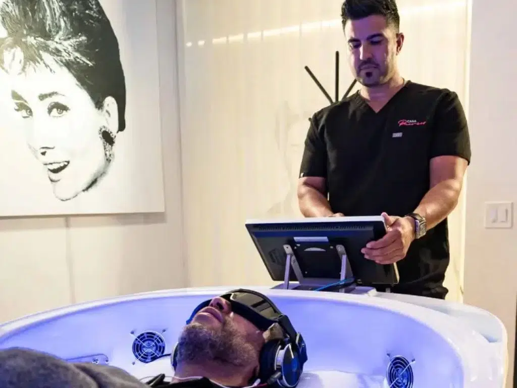 Skilled luxury medical technician at Casa Privée sets up a theta chamber in Miami. Session for treating addiction, stress, insomnia, and more.